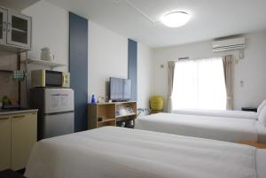 ein Hotelzimmer mit 2 Betten und einem TV in der Unterkunft STAY IN SUMUKA Kokusai Street in Naha