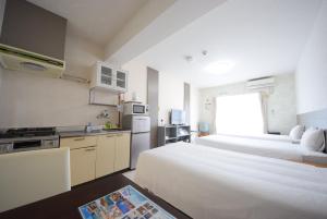 Habitación de hotel con 2 camas y cocina en STAY IN SUMUKA Kokusai Street, en Naha
