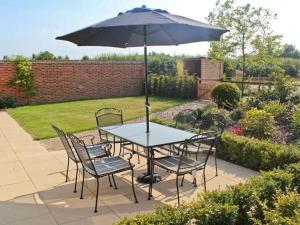 a table and chairs with an umbrella in a garden at Moat Farm Cottage in Wood Dalling