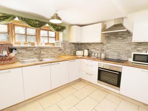 a kitchen with white cabinets and a sink at Loft Cottage in Bedale