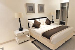 a white bedroom with a bed and two night stands at M Hotel Sorong in Sorong