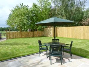 a table and chairs with an umbrella in a yard at Summer Farm Cottage in Bedale