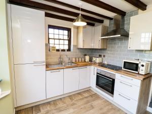 eine Küche mit weißen Schränken und einem Waschbecken in der Unterkunft King's Cottage in Bedale