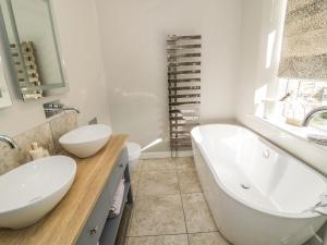 a bathroom with two sinks and a tub and a toilet at The Snug in Keighley