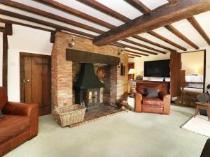 a living room with a brick fireplace and leather furniture at Harbourne Oast in Tenterden