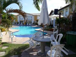 a table and chairs with an umbrella next to a pool at Apartamento Mont Carmelo in Porto Seguro