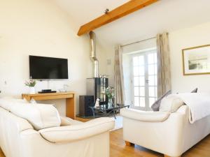 ein Wohnzimmer mit 2 weißen Sofas und einem TV in der Unterkunft Atlantic View in Tintagel