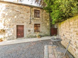 a table and chairs in front of a brick building at Garden Cottage in Mickleton