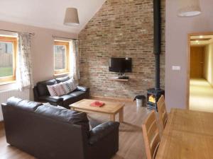 a living room with a couch and a brick wall at Pottowe Cottage in Potto