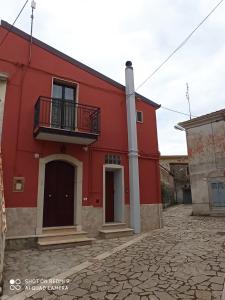 a red building with a balcony on a cobblestone street at L'altra casa 1933 in Rionero in Vulture