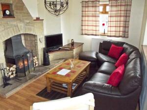 a living room with a leather couch and a fireplace at Hartam House in Falstone