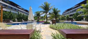 a pool with chairs and a table and a umbrella at Malawi Muro Alto - Flat 103H Térreo in Porto De Galinhas