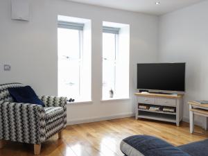 a living room with a television and a chair at 6 Mill Wharf in Berwick-Upon-Tweed
