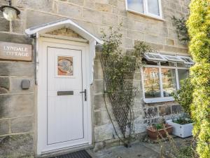 a white door on a stone building with a window at Lyndale Cottage in Robin Hood's Bay