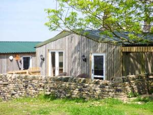 a wooden building with a stone wall and a fence at The Old Corn Store in Keighley