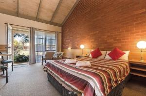 een slaapkamer met een groot bed met een bakstenen muur bij All Rivers Accommodation in Echuca