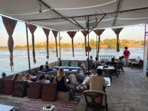 un gruppo di persone seduti ai tavoli vicino all'acqua di Opal privat nubian hotel a Aswan