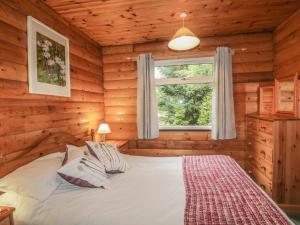 a bedroom with a bed in a log cabin at Otter Lodge in Strathpeffer