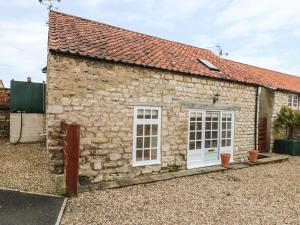 a stone cottage with white windows and a red roof at The Bothy, 21 West Street in Malton