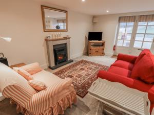 a living room with a red couch and a fireplace at The Bothy, 21 West Street in Malton