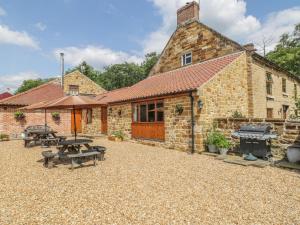 a brick building with picnic tables and a grill at Kitchen Cottage in Sutton