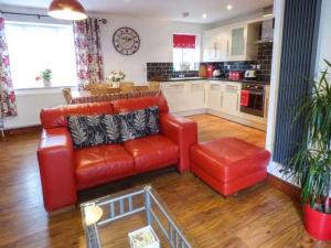 The Barn Ivy Cottage في Dunnington: غرفة معيشة مع أريكة حمراء ومطبخ