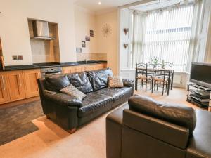a living room with a leather couch and a table at Flat 4 in Whitby