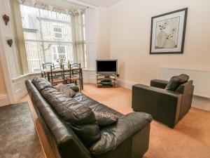 a living room with a leather couch and a television at Flat 4 in Whitby