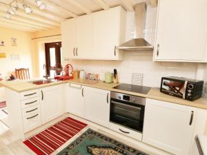 a kitchen with white cabinets and a stove top oven at Emily's Retreat at the Great Barn in Great Dunham