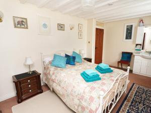a bedroom with a bed with blue pillows on it at Emily's Retreat at the Great Barn in Great Dunham