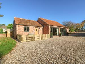 a brick house with a fence on a gravel driveway at The Cottage at Grange Farm Barns in Horncastle