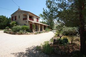 an old stone house with red windows and a driveway at Lou Cigalon in Cabrières-dʼAvignon