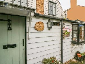 ウィスタブルにあるSwanfield Cottageの緑の扉と看板のある家