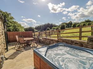 a hot tub on a patio with a table and chairs at Lake Farm Cottage in Ripon