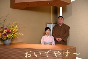 a man and a woman standing behind a counter at Gion Oyado Kikutani in Kyoto