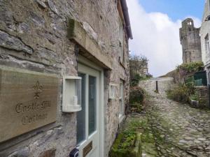 a stone building with a sign on the side of it at Castle Hill Cottage in Middleham