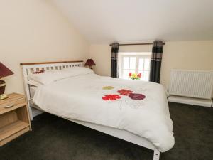 Church Farm Annex في ريبون: غرفة نوم بها سرير أبيض وعليه زهور