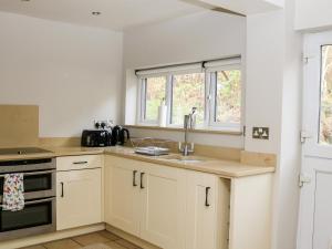 a kitchen with white cabinets and a sink and a window at 17 Riverside in Oakamoor