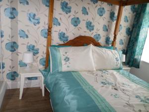 a bedroom with a bed with blue floral wallpaper at Sunrise Cottage in Lowestoft