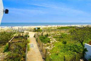 Eine Promenade, die zu einem Strand führt, an dem Leute sind. in der Unterkunft Pyramid in Ocean City