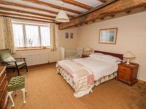 a bedroom with a bed and a chair and windows at The Old Hayloft in Great Edston