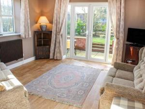 een woonkamer met een bank en een tapijt bij Primrose Cottage in Alford