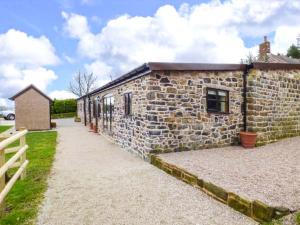 a stone building with a fence next to it at Upper Greenhills Farm in Foxt