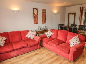 two red couches in a living room with wooden floors at Farley in Matlock