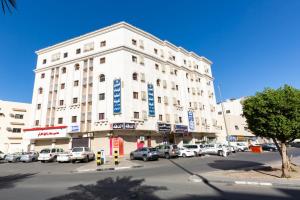 a large white building with cars parked in a parking lot at العييري للوحدات المفروشة المدينة 3 in Al Madinah