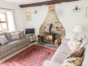 a living room with a stone fireplace and couches at Barn Cottage in West Burton
