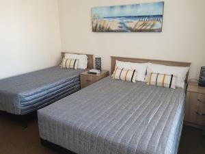 a bedroom with two beds and a painting on the wall at Sandpiper Motel Ulladulla in Ulladulla
