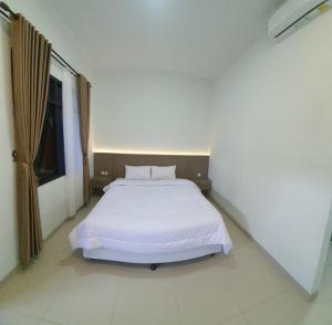 a bedroom with a white bed in a room at Joglo 21A in Yogyakarta