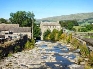 a river in a town with a building and buildings at Hillside View in Hawes