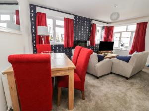 a living room with a wooden table and red chairs at Manor Heath - The Duplex in Scarborough